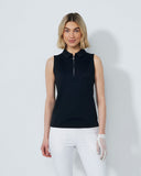 Woman wearing a black sleeveless top and white pants against a plain background