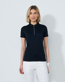 Woman wearing a black polo shirt and white pants on a light gray background