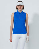 Woman wearing a blue sleeveless top and white pants on a gray background