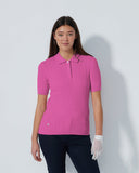 Woman wearing a pink polo shirt and dark pants on a white background