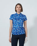 Woman wearing a blue patterned shirt and black pants on a white background