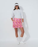 Woman wearing a white shirt, floral skirt, and visor on a white background