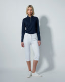 Woman wearing a navy long-sleeve top and white pants on a gray background