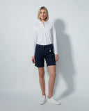 Woman wearing a white shirt and dark denim shorts on a plain background