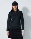 Woman wearing a black long-sleeve top and skirt with a visor on a white background