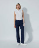 Woman wearing a sleeveless white blouse and dark blue pants on a plain background