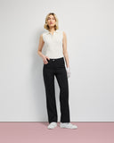 Woman wearing a white sleeveless top and black pants against a plain background