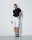 Person wearing a black polo shirt and white shorts against a plain background