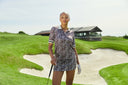 Girl wearing all brown with print standing on a golf course.