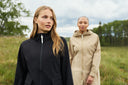 Close up of two girls walking in park wearing jackets.