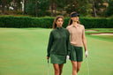 Two girls wearing green and beige walking on a golf course.