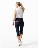 Woman wearing a white shirt and navy capri pants on a white background