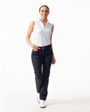 Woman wearing a white sleeveless top and dark pants on a white background