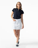 Woman wearing a black polo shirt and white skirt on a white background