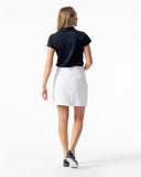 Woman wearing a black polo shirt and white shorts on a white background