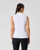 A woman viewed from behind wearing a white sleeveless collared golf polo shirt and black pants against a light gray studio background.