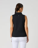 A woman viewed from the back wearing a sleeveless black collared polo-style top and white pants against a plain light gray studio background.