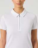 A woman wearing a white short-sleeve polo shirt with a half-zip collar, shown from the chest up against a light gray studio background.