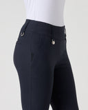 Close-up of a person wearing dark navy equestrian riding pants with a white textured shirt, shown from the waist down against a light gray studio background.