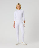 A woman modeling a white long-sleeve half-zip pullover and matching white fitted pants, standing against a plain light gray studio background.