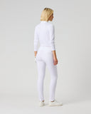 A blonde woman is shown from the back wearing a matching white long-sleeve mock-neck top and white leggings, paired with white sneakers, against a solid light gray studio background.