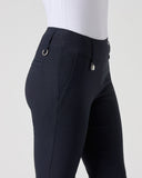 Close-up side view of a person wearing dark navy equestrian riding pants with a white top, shown against a light gray studio background.