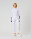 A woman modeling a white long-sleeve quarter-zip athletic top and matching white fitted pants, standing against a plain light gray studio background.