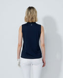 Woman wearing a navy sleeveless top and white pants on a light gray background