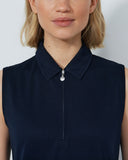 Woman wearing a navy sleeveless dress with a collar against a plain background