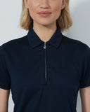 Person wearing a navy polo shirt against a plain background