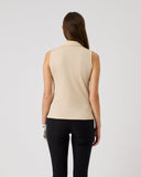 Woman wearing a beige sleeveless top and black pants on a plain background