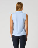 A woman viewed from the back wearing a light blue sleeveless collared top and dark navy leggings, standing against a plain light gray studio background.