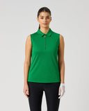 A woman modeling a sleeveless green polo shirt with a short front zipper, paired with black pants and a white golf glove, against a light gray studio background.