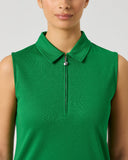 A close-up of a model wearing a bright green sleeveless polo shirt with a half-zip collar, shown against a neutral light gray background.