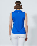 Woman wearing a blue sleeveless top and white pants on a light gray background