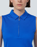 Woman wearing a blue sleeveless top with a collar on a plain background