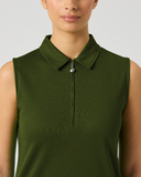 A woman wearing a sleeveless olive green polo-style top with a short front zipper and collar, shown against a light gray studio background.