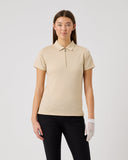 Woman wearing a beige polo shirt and black pants on a white background