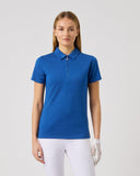 Woman wearing a blue polo shirt and white pants on a gray background