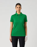 A woman modeling a bright green short-sleeve polo shirt with a half-zip collar, paired with black pants and a white golf glove, against a light gray studio background.