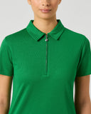 A woman wearing a bright green short-sleeve polo shirt with a half-zip collar, shown from the chest up against a light gray studio background.