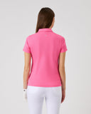 Woman wearing a pink polo shirt and white pants on a gray background