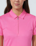 Person wearing a pink polo shirt with a zipper on a plain background