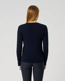 A woman viewed from the back wearing a dark navy ribbed knit sweater and dark leggings against a plain light gray studio background.