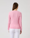 Person wearing a pink sweater and white pants on a light gray background