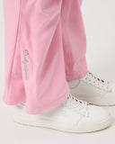 Person wearing pink pants with a brand logo and white sneakers on a light gray background