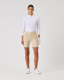 Woman wearing a white polo shirt and beige shorts on a light gray background