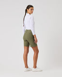 Woman wearing green shorts and a white shirt on a plain background