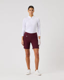 Woman wearing a white shirt and maroon shorts on a light gray background