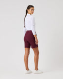 Person wearing maroon shorts and a white top on a light gray background